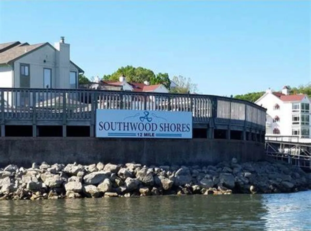A welcoming exterior view of the Southwood Shores sign, waterfront area, and surrounding buildings. The image conveys a community feel, with clear access to the lake and inviting spaces for both relaxation and exploration.