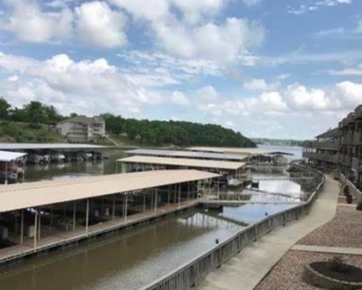 An exterior view of a peaceful marina, featuring calm water and surrounding greenery. The image captures marina docks where boats are moored, setting the scene for boating, fishing, or relaxing by the water.