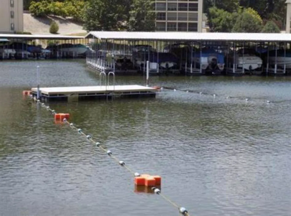 A serene exterior shot of the marina, featuring a floating dock with several boats moored and calm water reflecting the sky. The setting sun casts a warm glow, inviting people to fish off the dock, relax by the water, or gather for social activities at the marina.