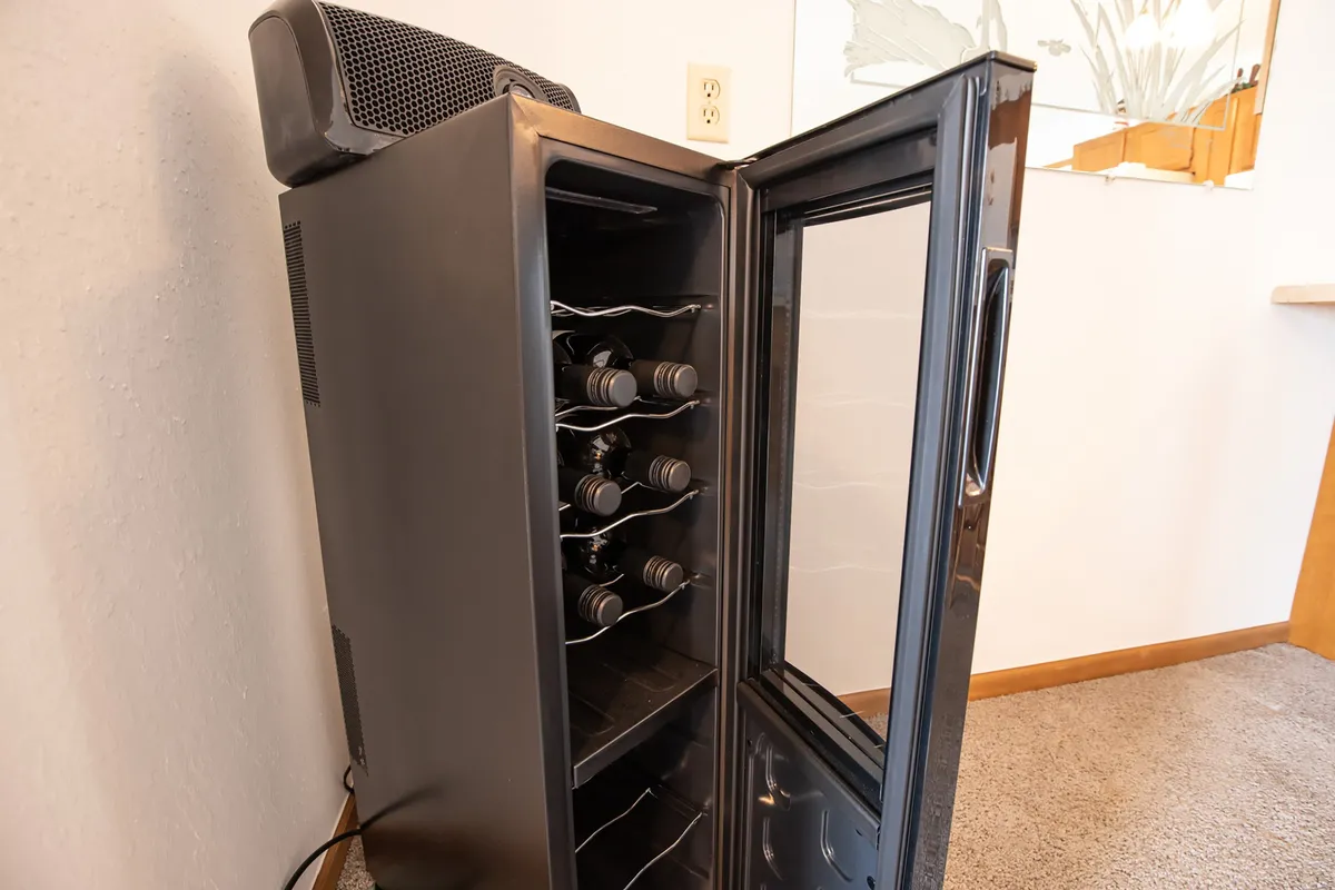 A sophisticated space centered around a wine cooler and shelves lined with wine bottles, surrounded by tasteful decor. The setting is perfect for intimate wine tastings or celebrating special moments with friends and family, echoing the concierge's tailored recommendations for local wine experiences.